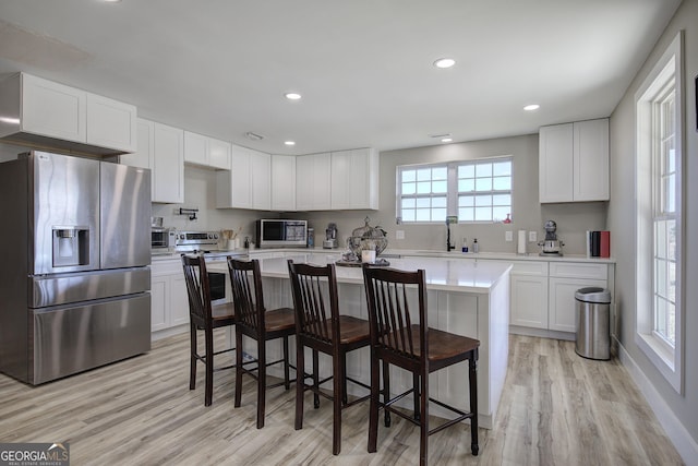 kitchen with stainless steel appliances, white cabinets, light countertops, and a sink