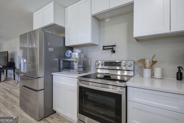 kitchen featuring light wood finished floors, appliances with stainless steel finishes, white cabinetry, and a toaster