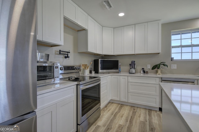 kitchen with light countertops, appliances with stainless steel finishes, visible vents, and white cabinetry