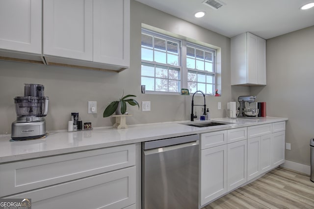 kitchen featuring visible vents, dishwasher, light wood-style flooring, white cabinetry, and a sink