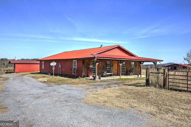 view of front of house with fence, metal roof, and an outbuilding