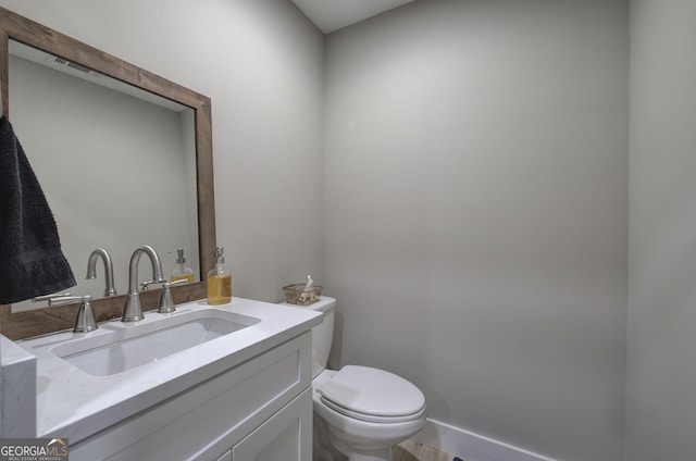 bathroom with toilet, baseboards, and vanity