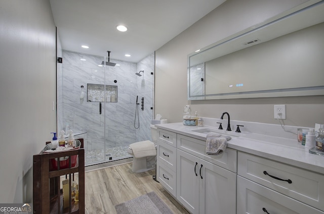 full bath with visible vents, toilet, vanity, a shower stall, and wood finished floors