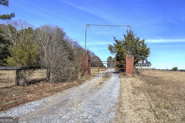 view of road featuring a gated entry, gravel driveway, and a gate