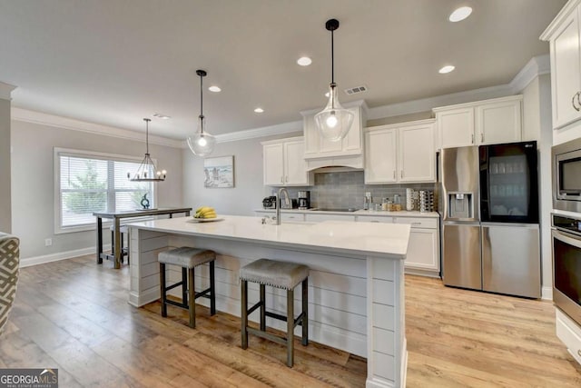 kitchen featuring appliances with stainless steel finishes, sink, pendant lighting, and white cabinets