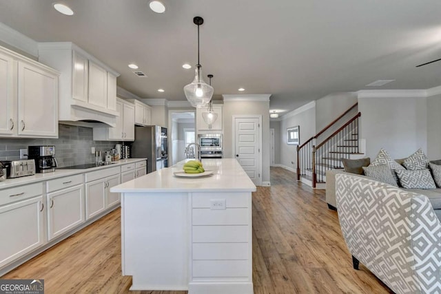 kitchen featuring white cabinetry, stainless steel appliances, a center island, light hardwood / wood-style floors, and decorative light fixtures