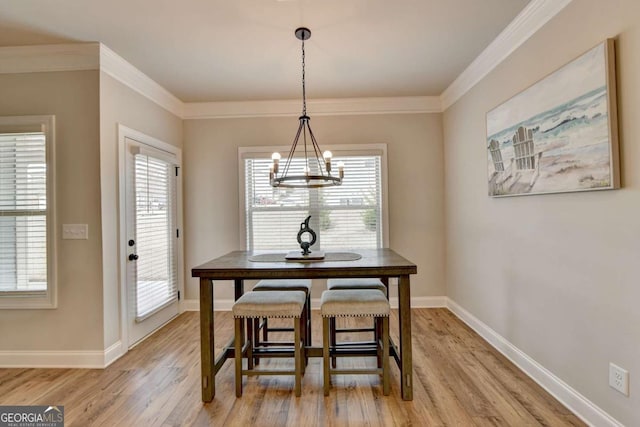 dining area with crown molding, a wealth of natural light, a chandelier, and light wood-type flooring