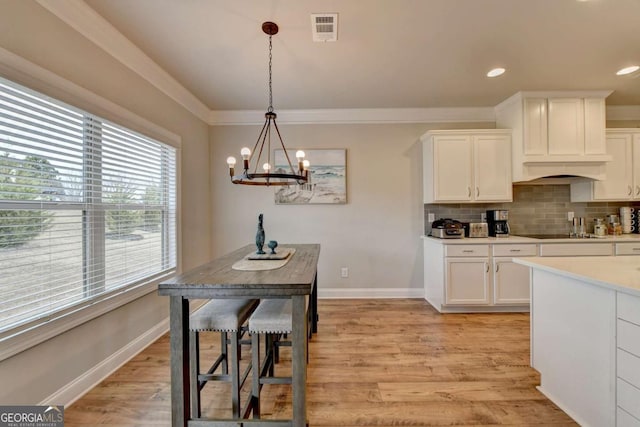 kitchen with white cabinetry, hanging light fixtures, backsplash, and light hardwood / wood-style flooring