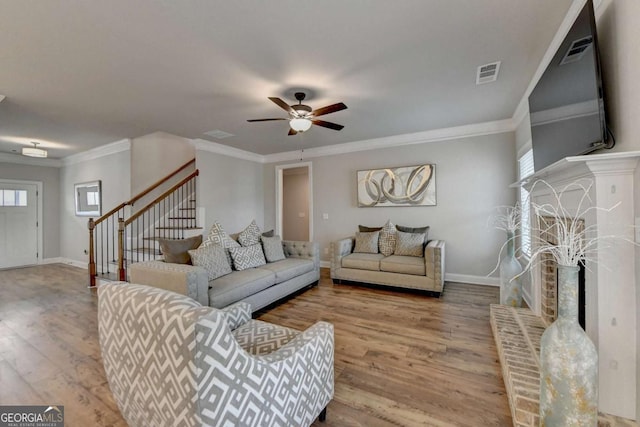 living room with a healthy amount of sunlight, crown molding, wood-type flooring, and ceiling fan