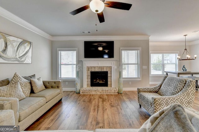 living room with crown molding, a healthy amount of sunlight, a brick fireplace, and hardwood / wood-style flooring