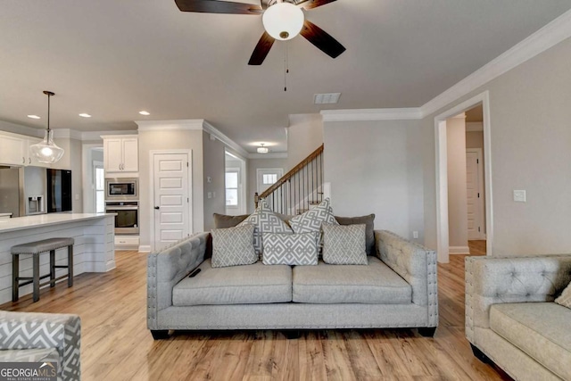 living room with crown molding, light hardwood / wood-style flooring, and ceiling fan