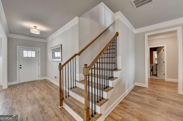 entrance foyer featuring ornamental molding and light hardwood / wood-style floors