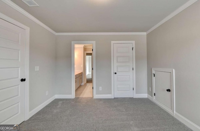 unfurnished bedroom with crown molding, light colored carpet, and ensuite bath