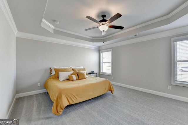 carpeted bedroom featuring ceiling fan, ornamental molding, and a tray ceiling