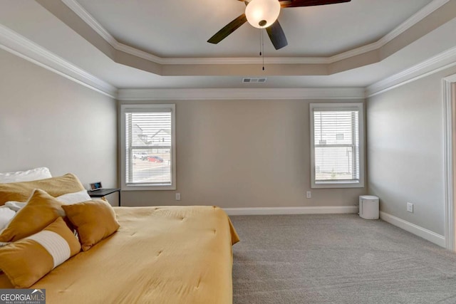 carpeted bedroom featuring multiple windows, ornamental molding, and a raised ceiling