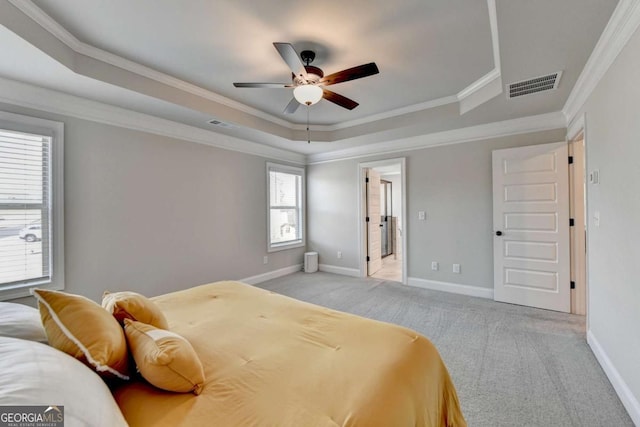 bedroom featuring a raised ceiling, ornamental molding, light carpet, and ceiling fan