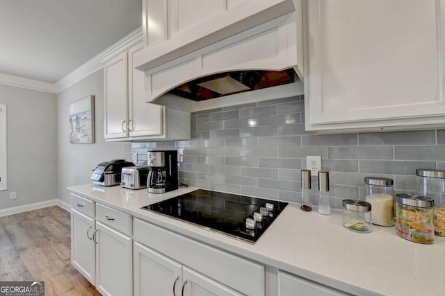 kitchen featuring white cabinetry, tasteful backsplash, ornamental molding, black electric cooktop, and custom exhaust hood