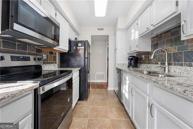 kitchen with white cabinetry, sink, decorative backsplash, light stone counters, and stainless steel appliances