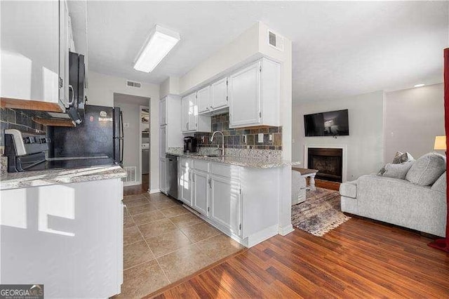 kitchen featuring white cabinetry, light stone counters, hardwood / wood-style flooring, stainless steel appliances, and backsplash