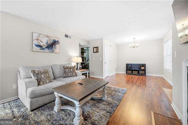 living room featuring hardwood / wood-style flooring, a textured ceiling, and a chandelier