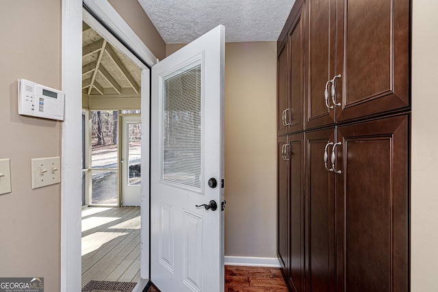 interior space featuring baseboards, dark wood finished floors, and a textured ceiling