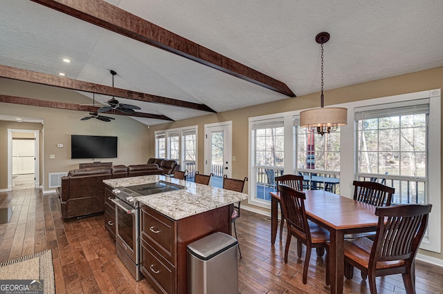 kitchen featuring open floor plan, a center island, vaulted ceiling with beams, high end stainless steel range oven, and decorative light fixtures