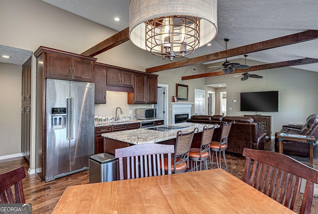 kitchen with dark wood-style flooring, a sink, dark brown cabinets, appliances with stainless steel finishes, and beam ceiling