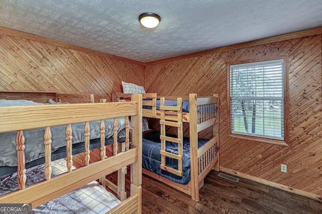 bedroom featuring dark wood-style flooring, wood walls, and a textured ceiling