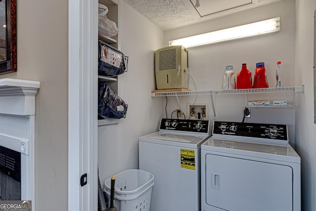 clothes washing area featuring laundry area, a textured ceiling, and washer and dryer