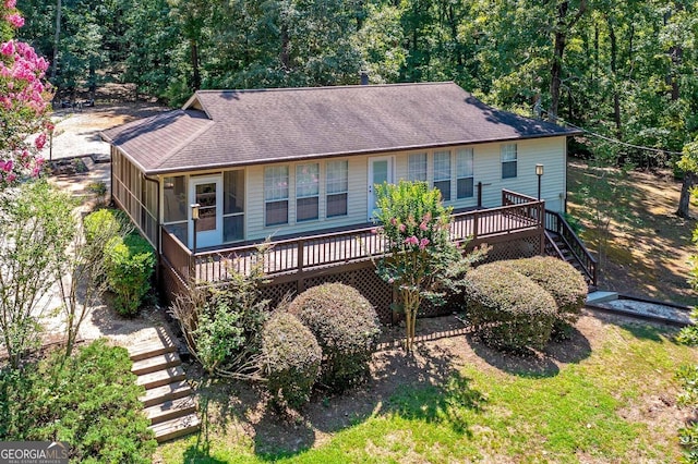 view of front of house with roof with shingles, stairway, a wooden deck, and a sunroom