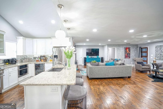 kitchen featuring beverage cooler, white cabinets, dark wood-type flooring, stainless steel appliances, and a sink