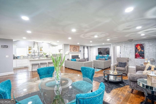 living area with a fireplace, baseboards, wood finished floors, and recessed lighting