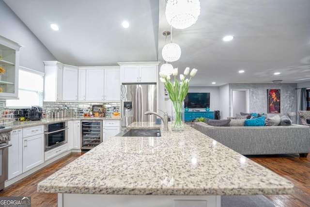 kitchen featuring wine cooler, a large island, stainless steel appliances, white cabinetry, and a sink