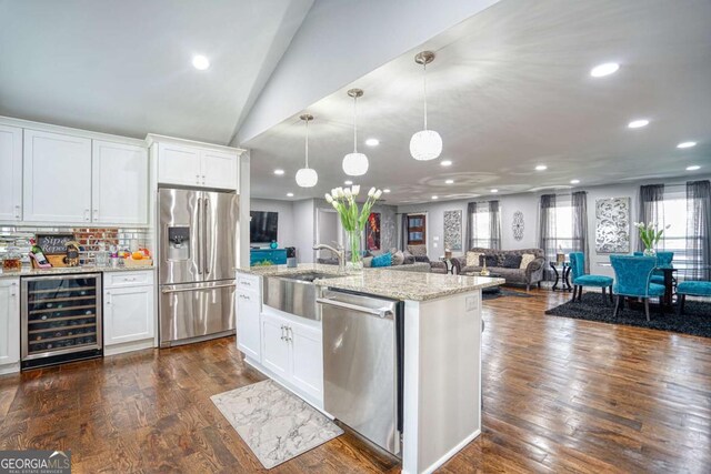 kitchen with beverage cooler, stainless steel appliances, dark wood-type flooring, open floor plan, and light stone countertops