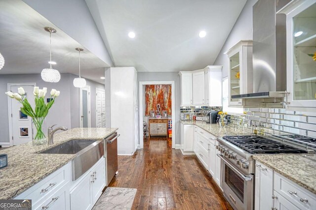 kitchen with dark wood-style floors, appliances with stainless steel finishes, a sink, light stone countertops, and wall chimney exhaust hood