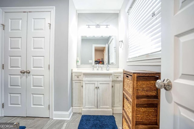 bathroom with a closet, vanity, and baseboards