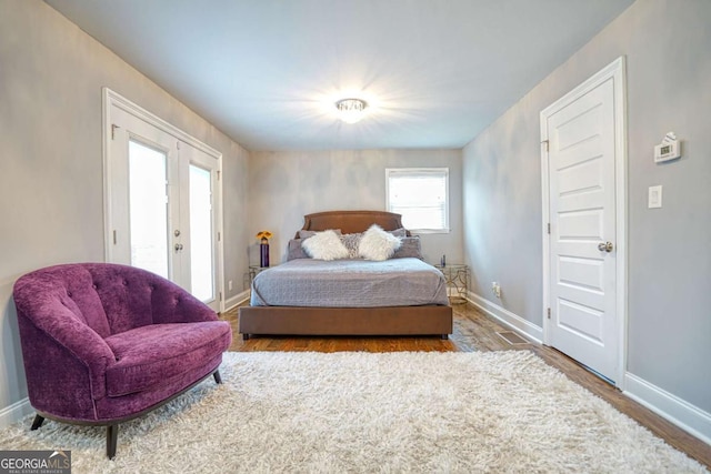 bedroom with baseboards, wood finished floors, and french doors