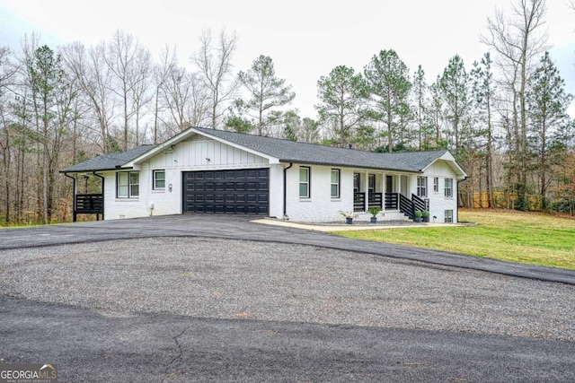 ranch-style house with aphalt driveway, a shingled roof, board and batten siding, a front yard, and a garage