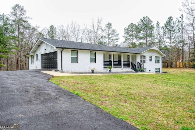 ranch-style home with aphalt driveway, a porch, an attached garage, board and batten siding, and a front yard