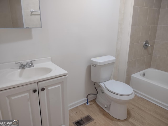 full bathroom with vanity, hardwood / wood-style floors, tiled shower / bath, and toilet