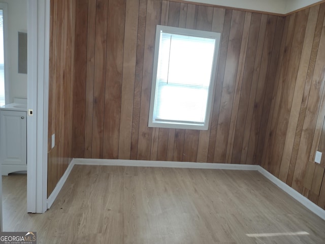 spare room featuring light wood-type flooring and wooden walls