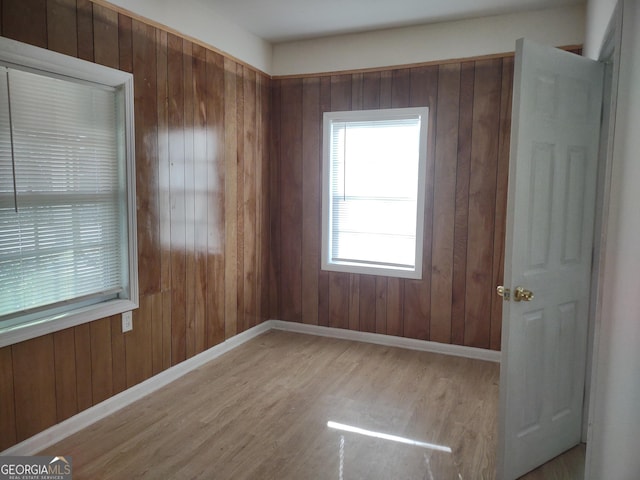 empty room with light hardwood / wood-style floors and wood walls