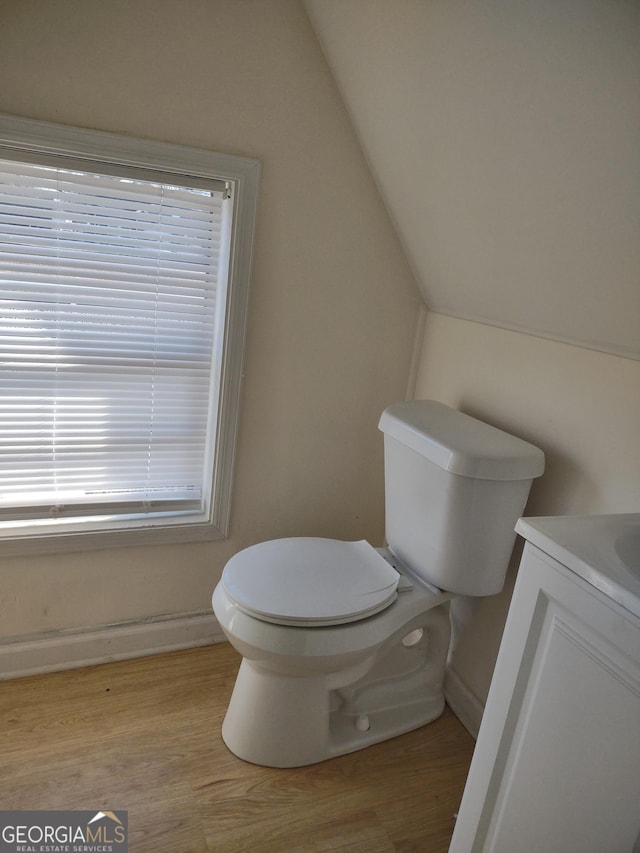 bathroom featuring lofted ceiling, toilet, hardwood / wood-style floors, and vanity