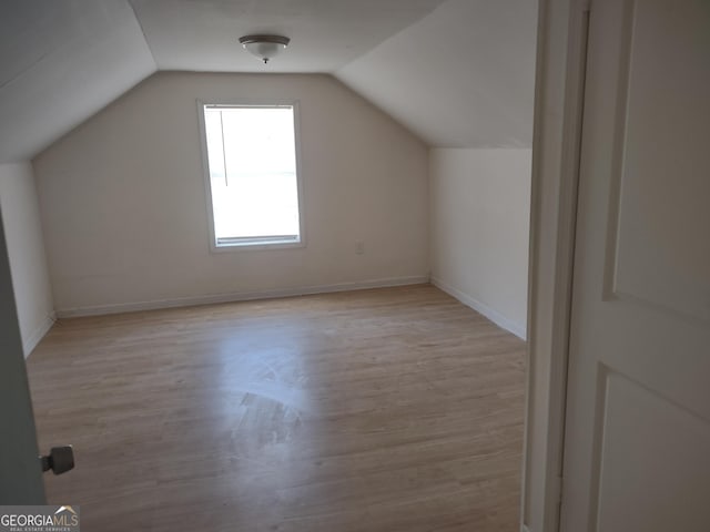 additional living space with lofted ceiling and light hardwood / wood-style flooring