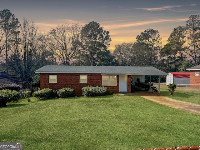 ranch-style house featuring a carport and a lawn