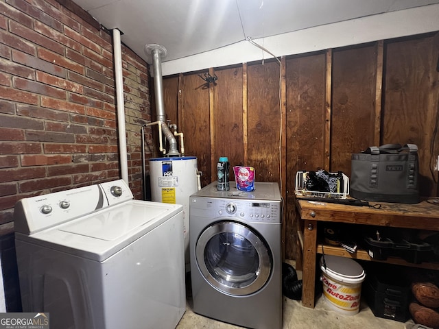 clothes washing area featuring washer and clothes dryer, laundry area, and brick wall