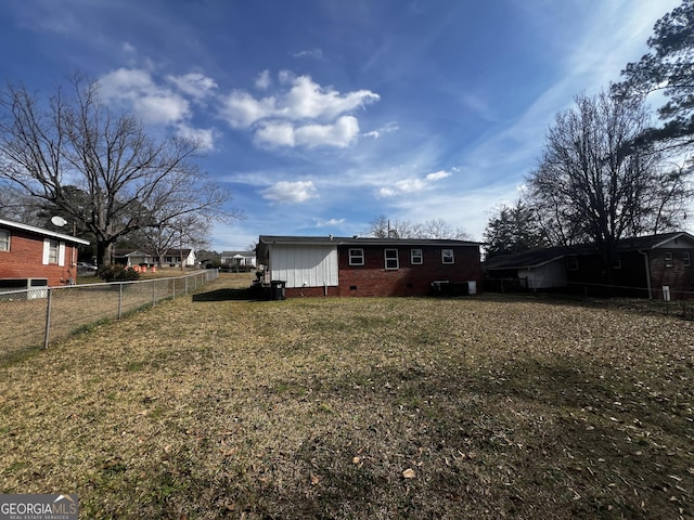 rear view of house with crawl space, a lawn, and fence