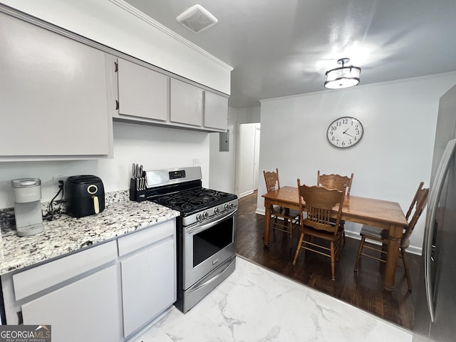 kitchen with light stone countertops, stainless steel range with gas cooktop, marble finish floor, and crown molding