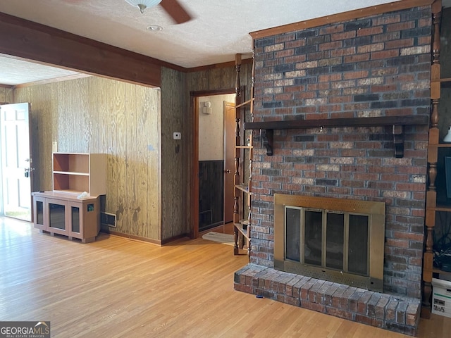 living room with crown molding, light hardwood / wood-style floors, a textured ceiling, beamed ceiling, and wood walls