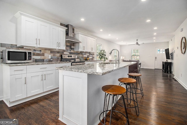 kitchen featuring appliances with stainless steel finishes, sink, white cabinets, and wall chimney exhaust hood